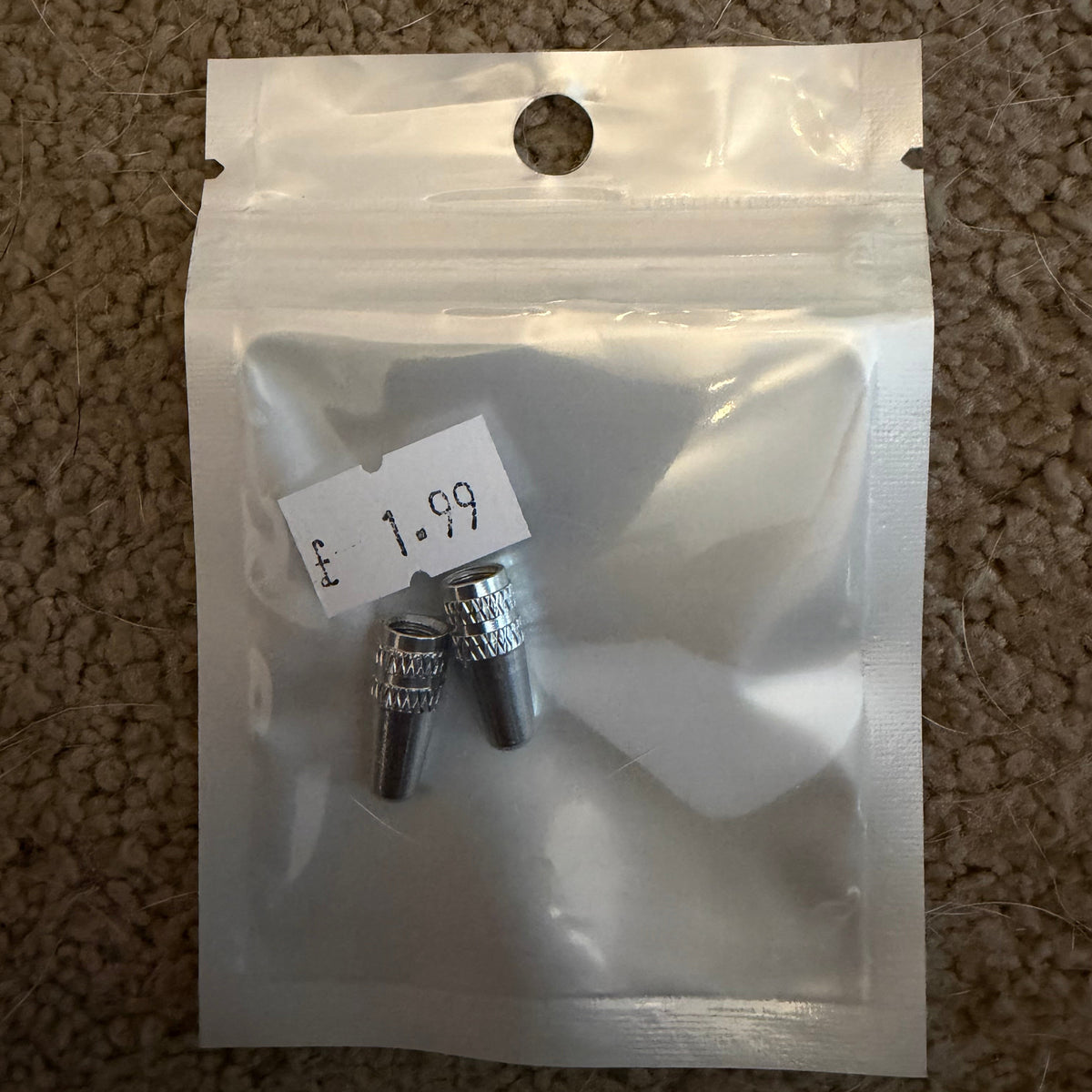Aluminium Presta Valve Caps, shiny silver knurled cylindrical caps with textured grips, stacked in front of a small pouch.