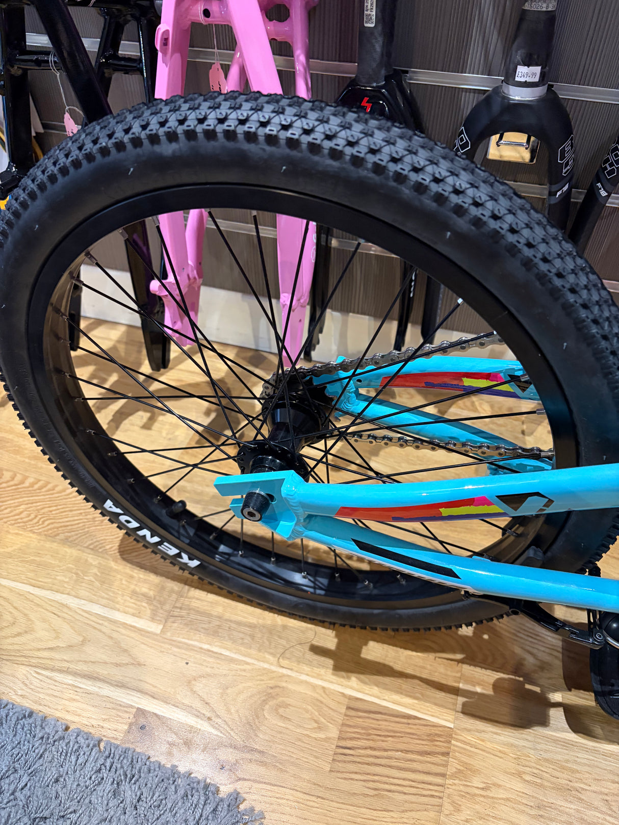 Bombshell Aluminium wheelset Pro 36H V-Brake Black IN STOCK on black rim with knobby tire, blue frame and pink fork visible