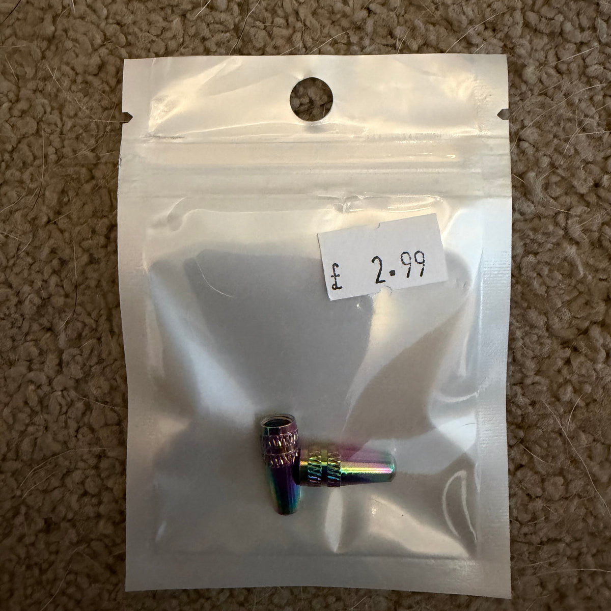 Aluminium Presta Valve Caps in rainbow hues, knurled cylindrical caps with ribbed texture, shown on a silver pouch tag....