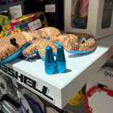Aluminium Presta Valve Caps in bright blue, cone shaped with knurled facets and glossy finish displayed atop a shelf now.