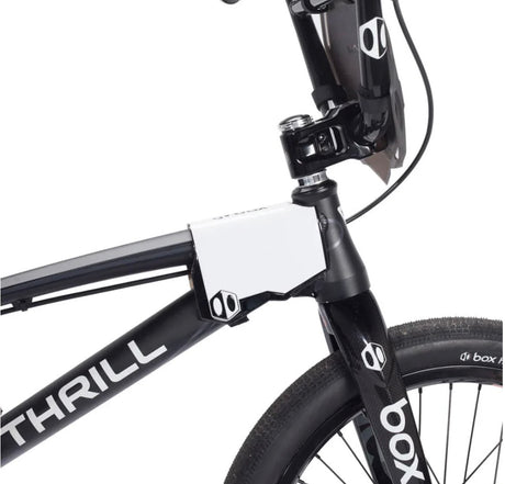 Box Two BMX Side Number Plate by SSS Racing, white aluminum plate with black accents mounted on a black frame nearby fork.