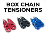 Box Two Chain Tensioners by SSS Racing in red, black, and blue anodized aluminum with silver bolts and circular finger holes.