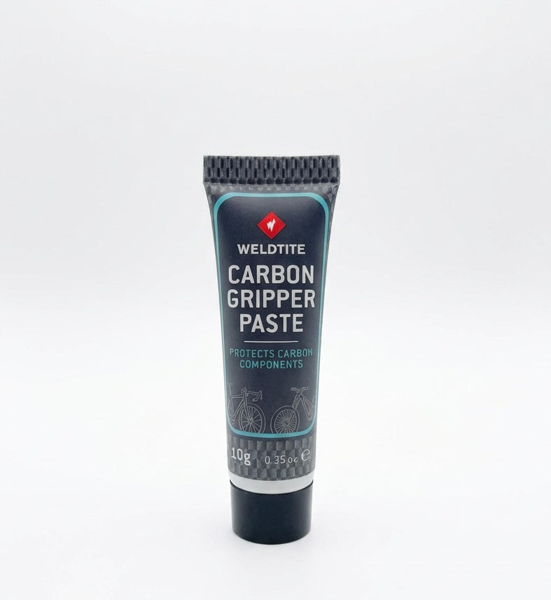 SSS Racing Carbon Fibre Gripper Paste tube: dark blue body, teal trim, silver cap, carbon graphics, 10g squeeze tube on desk