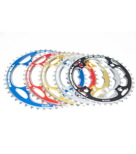 Bombshell Chainring in blue red gold silver titanium-coated alloy with sharp serrated teeth and bold cutouts. BMX racing. 