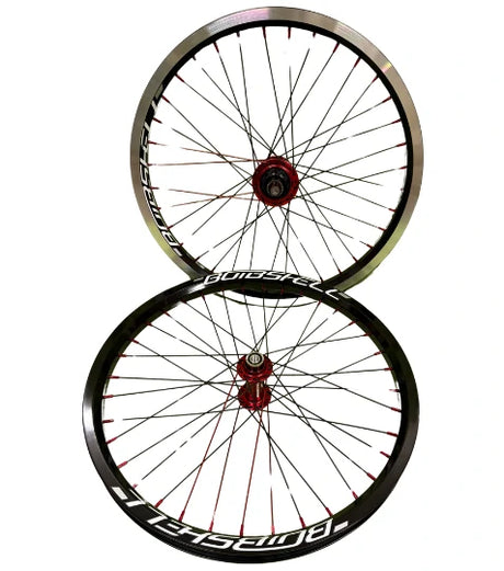 Two BMX racing wheels with black rims and red hubs on a white background