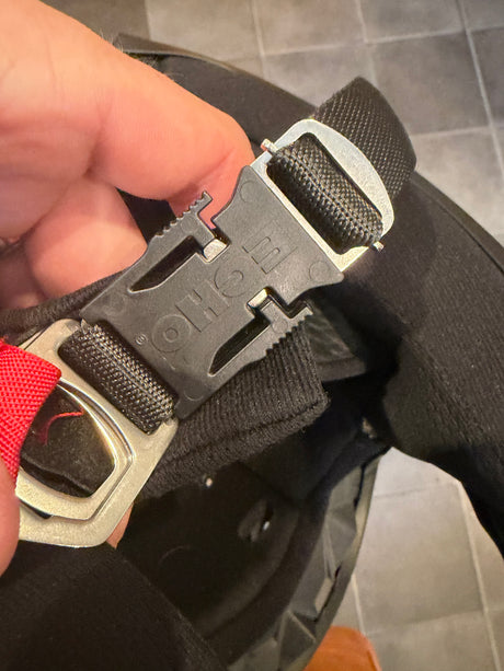 Echo Quick Release Helmet Buckle on a black strap with metallic gray buckle, red strap tab, and jagged release lever detail.