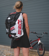 Bombshell Training Kit Bag backpack in black and white with red logo panels, padded straps, rectangular shape worn by rider.