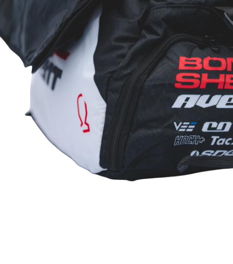 Bombshell Training Kit Bag in black with white side panel, red logo text, square form, visible zip, bold athletic branding.