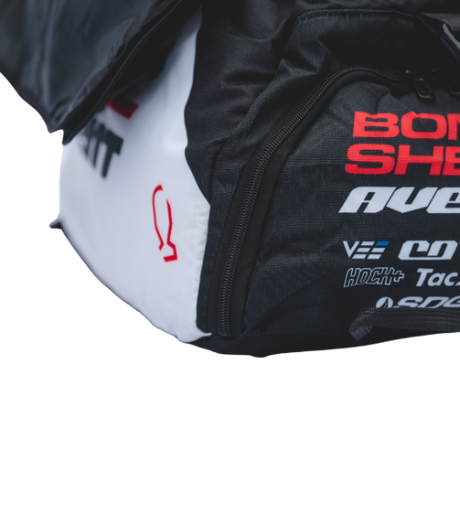 Bombshell Training Kit Bag in black with white side panel, red logo text, square form, visible zip, bold athletic branding.